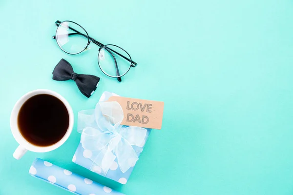 Mutlu babalar günü kavramı. Mavi kravat üst görünümü, güzel hediye kutusu, kahve bardağı, parlak yeşil pastel arka plan üzerinde Love Dad metin ile gözlük. — Stok fotoğraf