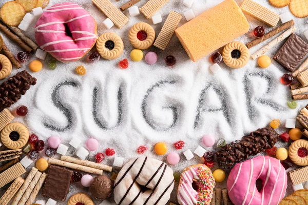 Food containing sugar. mix of sweet donuts, cakes and candy with sugar spread and written text in unhealthy nutrition, chocolate abuse and addiction concept, body and dental care. — Stock Photo, Image