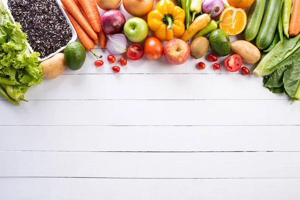 Un stil de viață sănătos și un concept alimentar. Vedere de sus a legumelor proaspete, fructelor, ierburilor și condimentelor cu o farfurie pastelată roz goală pe fundal din lemn alb . — Fotografie, imagine de stoc