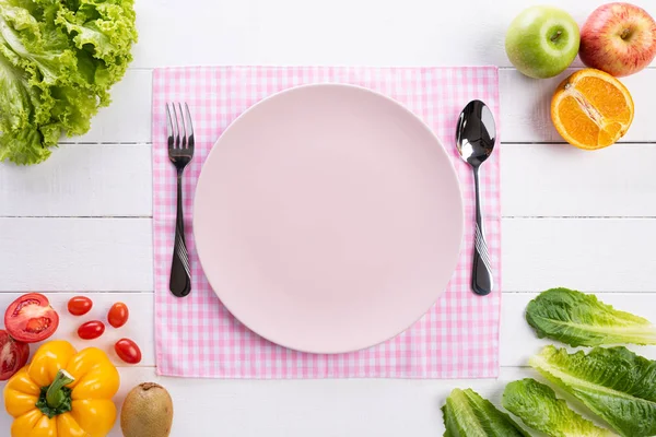 Здоровий спосіб життя та концепція їжі. Вид зверху на свіжі овочі, фрукти, трави та спеції з порожньою рожевою пастельною тарілкою на білому дерев'яному фоні . — стокове фото