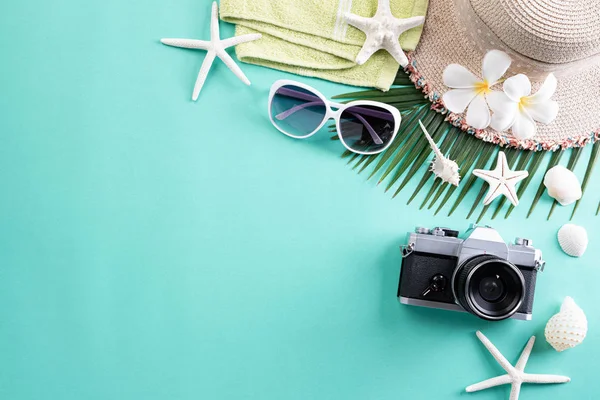 Plaj aksesuarları Retro Film Kamera, güneş gözlüğü, Flip flop yıldız balığı plaj şapka ve yaz tatili ve tatil konsepti için yeşil pastel arka plan üzerinde deniz kabuğu.