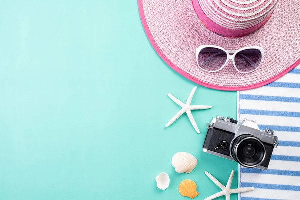 Plaj aksesuarları Retro Film Kamera, güneş gözlüğü, Flip flop yıldız balığı plaj şapka ve yaz tatili ve tatil konsepti için yeşil pastel arka plan üzerinde deniz kabuğu.