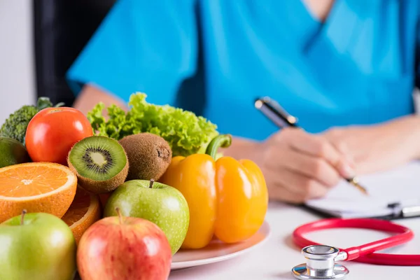 Mode de vie sain, nourriture et concept de nutrition. Gros plan de fruits et légumes frais avec stéthoscope sur le bureau du médecin . — Photo