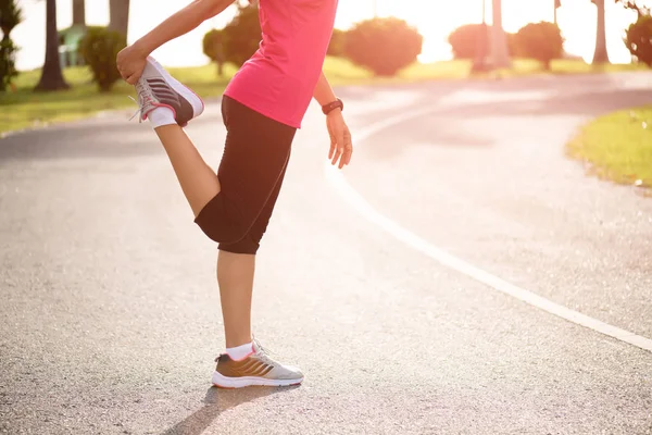 Jovem corredor mulher fitness esticando as pernas antes de correr no parque. Conceito de atividades de exercício ao ar livre . — Fotografia de Stock