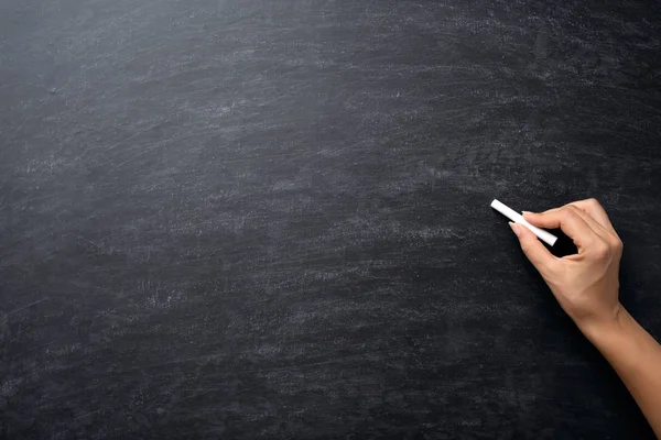 Utbildning eller tillbaka till skolan konceptet. Kvinna hand hållande krita över svarta tavlan bakgrund. — Stockfoto