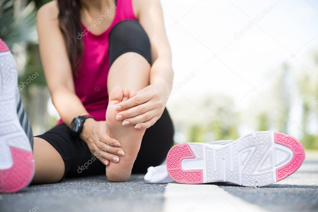 Young woman massaging her painful foot while exercising. Running Sport and excercise injury concept.