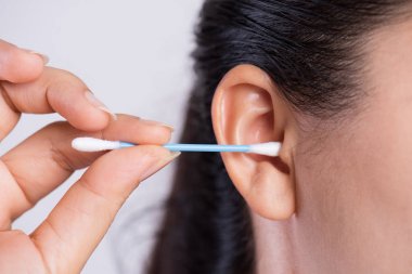 Pamuklu bez ile kulak temizleme genç Asyalı kadın kapatın. Sağlık ve kulak temizleme konsepti.