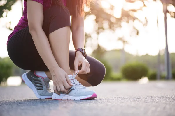 Löparskor - närbild av kvinna knyta skosnören. Kvinnliga sport fitness löpare redo för jogging i trädgården bakgrunden. — Stockfoto