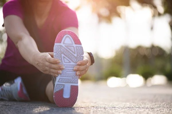 Genç Fitness kadın Runner parkta çalıştırmadan önce bacaklar germe yolda oturmak. Açık egzersiz aktiviteleri konsepti. — Stok fotoğraf