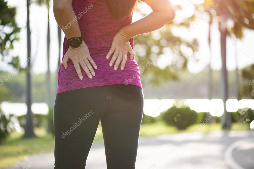 Young asian woman feel pain on her back and hip while exercising, health care concept.