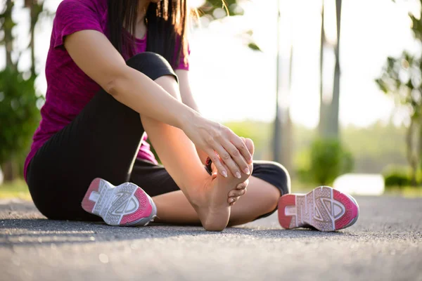 Ung kvinna massera hennes smärtsamma fot medan du tränar. Löpning sport och motion skade koncept. — Stockfoto