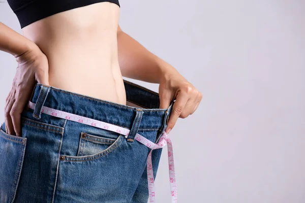 Bliska Szczupła młoda kobieta mierząc jej cienką talię z centymetrem. Opieka zdrowotna i kobieta dieta styl życia, aby zmniejszyć brzuch i kształtować zdrowe mięśnie brzucha. — Zdjęcie stockowe