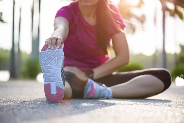 Genç Fitness kadın Runner parkta çalıştırmadan önce bacaklar germe yolda oturmak. Açık egzersiz aktiviteleri konsepti. — Stok fotoğraf