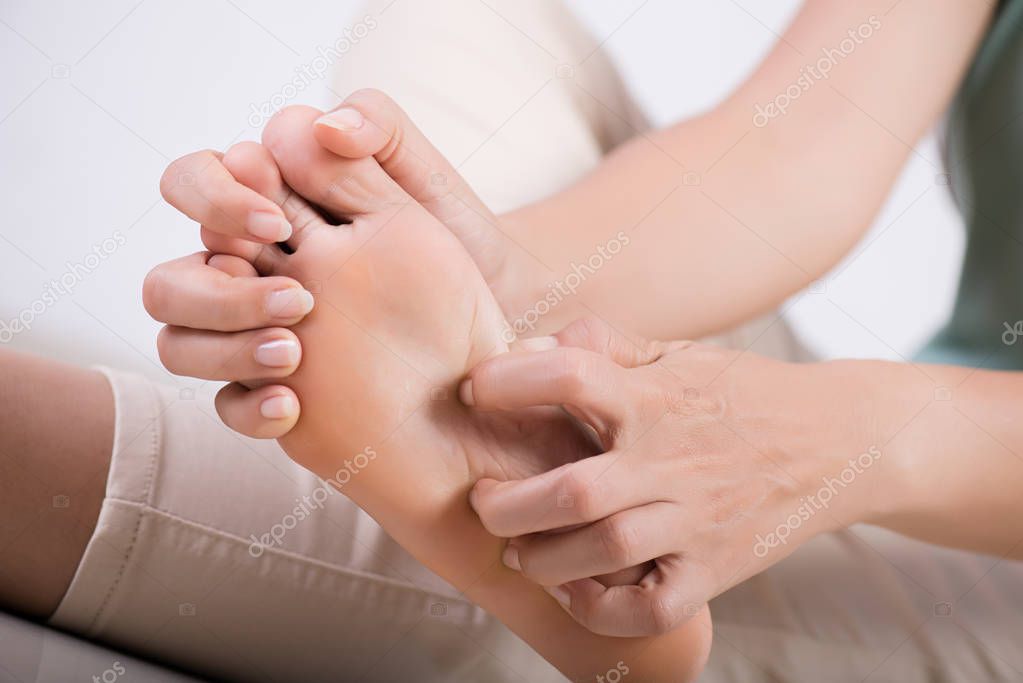 Close up woman foot scratch the itch by hand at home. Healthcare and medical concept.