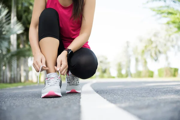 Running shoes - closeup of woman tying shoe laces. Female sport fitness runner getting ready for jogging in garden background. — Stock Photo, Image