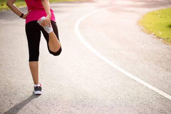 Joven corredor de fitness mujer estirando las piernas antes de correr en el parque. concepto de actividades de ejercicio al aire libre . — Foto de Stock