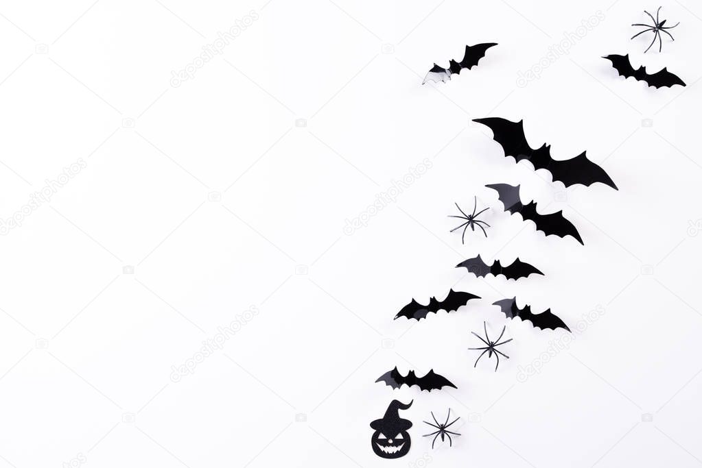 Top view of Halloween crafts, black paper ghost, spider and bats flying over white background with copy space for text. halloween concept.