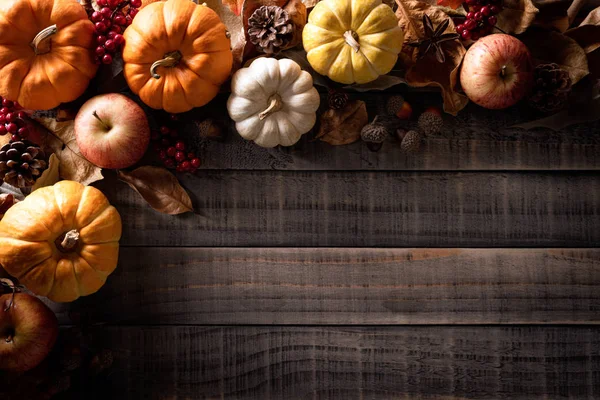 Κάτοψη του σφενδάμνου φθινόπωρο φύλλα με κολοκύθι, μήλο, καλαμπόκι και κόκκινα μούρα σε παλιό ξύλινο υπόβαθρο. Ημέρα των Ευχαριστιών έννοια. — Φωτογραφία Αρχείου