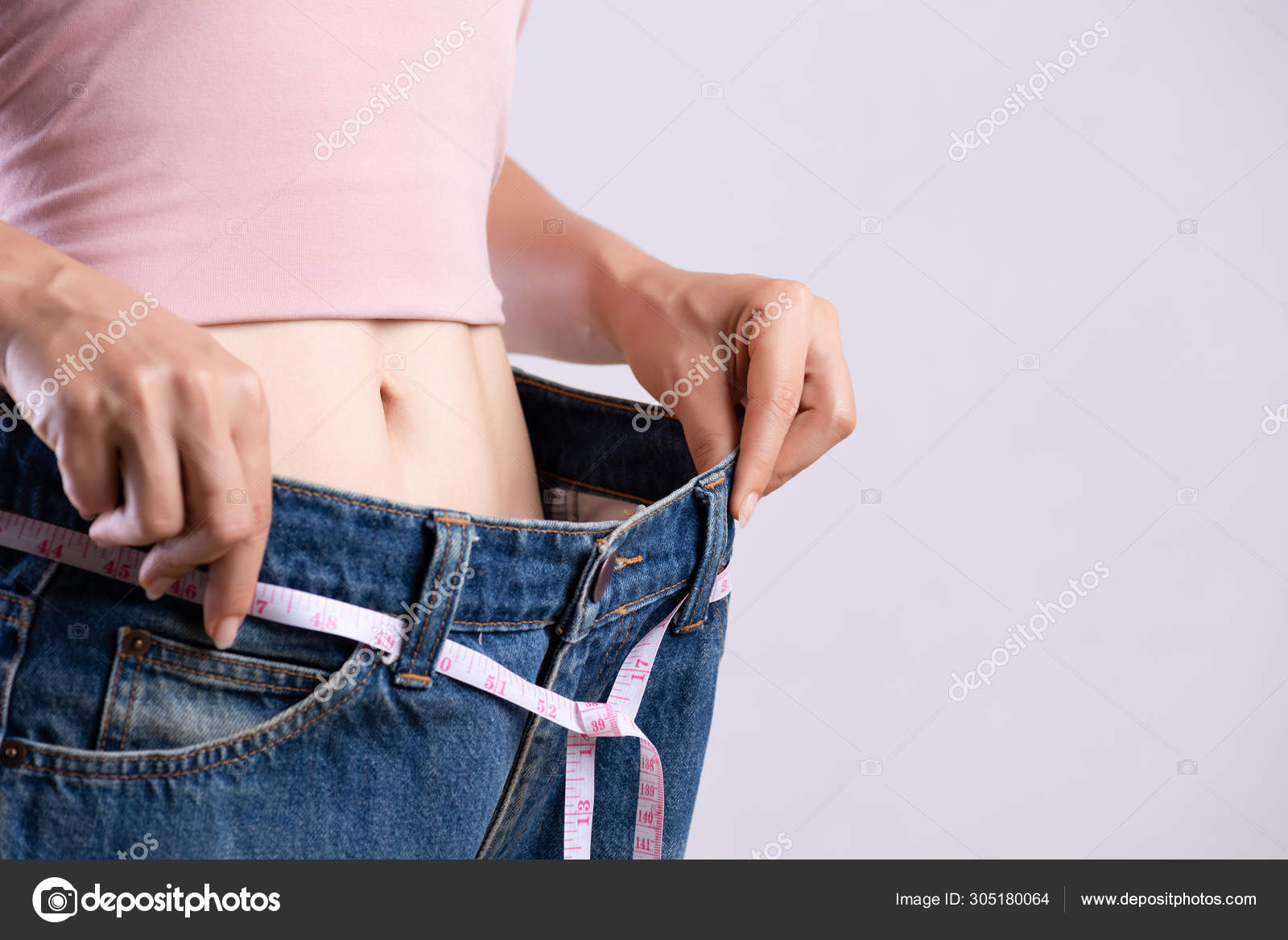 Closeup Of A Young Woman Measuring Her Waist With A Tape Measure