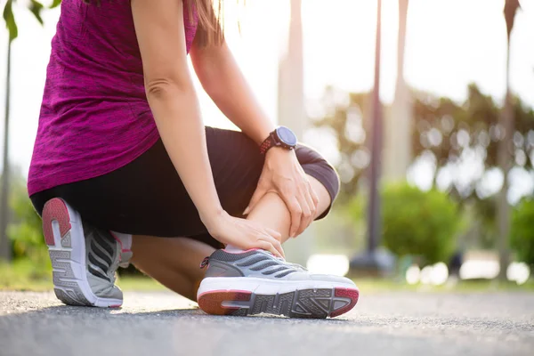 Caviglia slogata. Giovane donna che soffre di un infortunio alla caviglia durante l'esercizio e la corsa. Concetto di sanità e sport . — Foto Stock