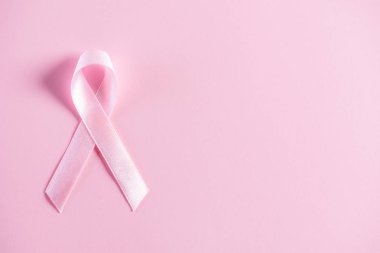 Göğüs kanseri farkındalığı kampanyasını desteklemek için pembe pastel kağıt üzerine pembe kurdele..