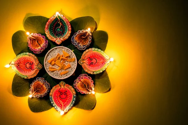 Feliz Dussehra. Lámparas de arcilla Diya encendidas durante Dussehra con flores amarillas, hojas verdes y arroz sobre fondo amarillo pastel. Dussehra Indian Festival concepto . —  Fotos de Stock