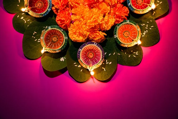 Feliz Dussehra. Lámparas de arcilla Diya encendidas durante Dussehra con flores amarillas, hojas verdes y arroz sobre fondo pastel rosado. Dussehra Indian Festival concepto . — Foto de Stock