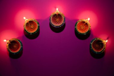 Mutlu Diwaliler - Dipavali sırasında Clay Diya lambaları yandı, Hindu ışık festivali kutlaması. Pembe arka planda renkli geleneksel gaz lambası diya