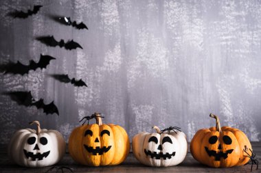 Gri tahta arka planda sopalı cadı şapkalı turuncu hayalet balkabakları. Cadılar Bayramı konsepti.