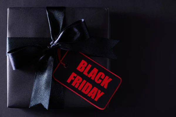 Draufsicht auf schwarze Weihnachtsboxen mit rotem Papieranhänger auf schwarzem Hintergrund mit Kopierraum für Text. Black-Friday-Komposition. — Stockfoto