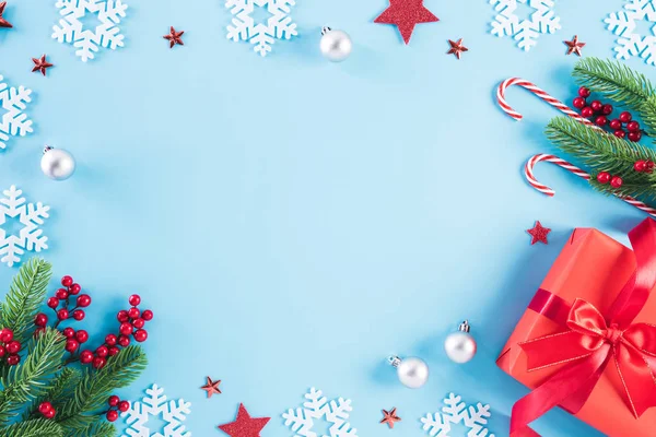 Χριστουγεννιάτικη σύνθεση Πάνω όψη κόκκινου κουτιού δώρου με διακόσμηση χριστουγεννιάτικου δέντρου και κόκκινα μούρα σε μπλε παστέλ φόντο με χώρο αντιγραφής για κείμενο. — Φωτογραφία Αρχείου