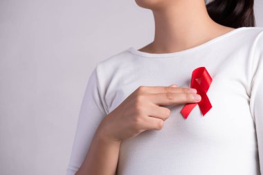AIDS Günü 'nü desteklemek için göğsüne kırmızı rozet kurdelesi takıldı. Sağlık, ilaç ve AIDS farkındalığı kavramı.