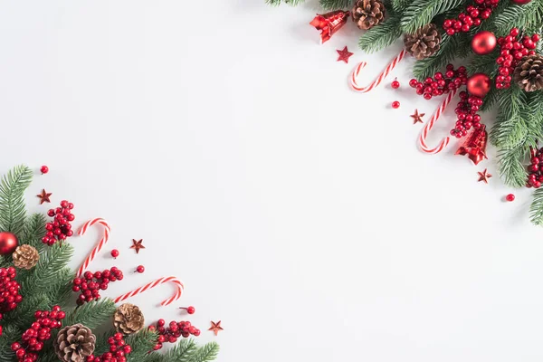 Weihnachtshintergrundkonzept. Ansicht der Weihnachtsgeschenkbox rote Kugeln mit Fichtenzweigen, Tannenzapfen, roten Beeren und Glocke auf weißem Hintergrund. — Stockfoto