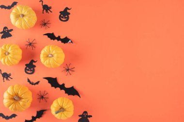 Cadılar Bayramı el sanatları, sarı balkabağı, hayalet, yarasa ve örümceğin turuncu zemin üzerindeki görüntüsü ve metin için fotokopi alanı. Cadılar Bayramı konsepti.