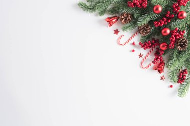 Noel arka plan kavramı. Beyaz arka plan üzerinde Noel hediye kutu kırmızı topları çam dalları, çam kozalakları, kırmızı meyveler ve bell ile üstten görünüm.