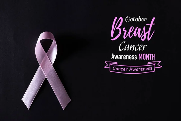 Różowa wstążka na czarnym tle papieru do wspierania kampanii miesiąc świadomości raka piersi. — Zdjęcie stockowe