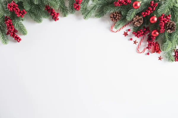 Χριστουγεννιάτικο φόντο έννοια. Το Top view χριστουγεννιάτικο δώρο κουτί κόκκινο μπάλες με ερυθρελάτη κλαδιά, κουκουνάρια, κόκκινα μούρα και κουδούνι σε λευκό φόντο. — Φωτογραφία Αρχείου