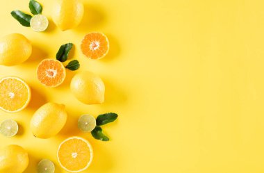 Yaz kompozisyonu portakallar, limon ve yeşil yapraklar ve pastel sarısı arka plan. Meyve asgari konsept. Düz konum, üst görünüm, kopyalama alanı.