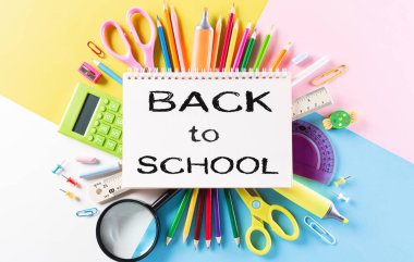 Eğitim ya da okula dönüş konsepti. Renkli okul gereçleri, kitaplar, renkli kalemler, hesap makinesi, ataçlar ve pastel kağıt üzerine elma. Düz yatıyordu.