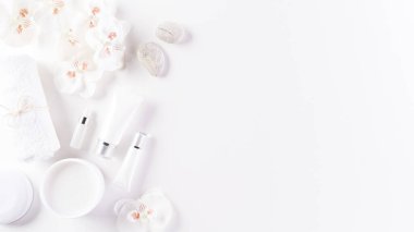 Kozmetik şişe kapları, çiçekli cilt kremi. Doğal güzellik ve kaplıca konsepti, beyaz masa arka planında üstten görünüm.