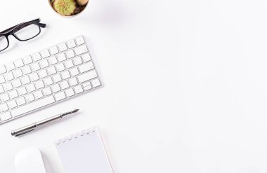 Üst kattaki ofis masasında yatıyordu. Klavyeli çalışma alanı, ofis malzemeleri ve beyaz arkaplanda kopya alanı olan kalem.