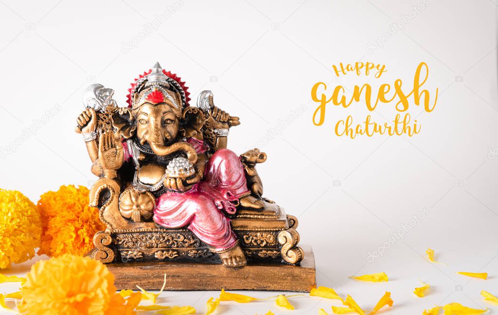 Happy Ganesh Chaturthi festival, Bronze Ganesha statue and Golden texture with flowers, Ganesh is hindu god of Success.
