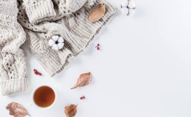 Sonbahar kompozisyonu. Bir fincan kahve, pamuk çiçekleri, sonbahar yaprakları ve beyaz arka planda kadın süveteri. Düz konum, kopyalama alanı olan üst görünüm.