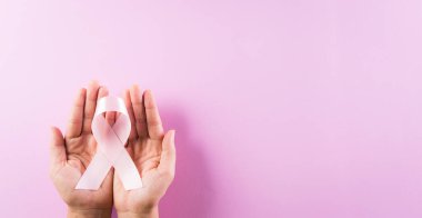 Pembe kurdele tutan eller, göğüs kanseri farkındalığı, sembolik yay rengi kadınların göğüs tümöründe farkındalık yaratıyor. Sağlık, tıp ve göğüs kanseri farkındalığı.