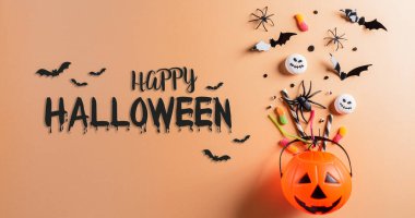 Cadılar Bayramı el sanatları, turuncu balkabağı, hayalet, yarasa ve turuncu arka planda siyah örümcek. Düz yatış, üst görünüm Mutlu Cadılar Bayramı metni.