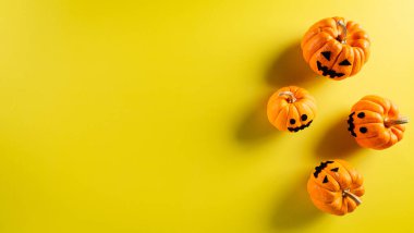 Cadılar Bayramı süslemeleri pastel sarısı arka planda hayalet balkabağından yapılmış. Düz konum, metin için kopyalama alanı olan üst görünüm.