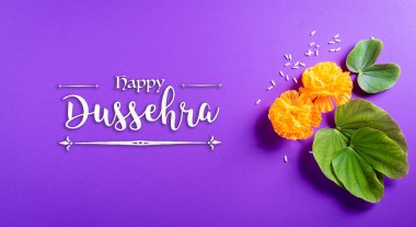 Mutlu Dussehra. Sarı çiçekler, yeşil yaprak ve mor pastel arka planda pirinç. Dussehra Hint Festivali konsepti.