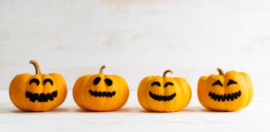 Beyaz ahşap arkaplanda sarı hayalet balkabakları. Cadılar Bayramı dekorasyon konsepti.