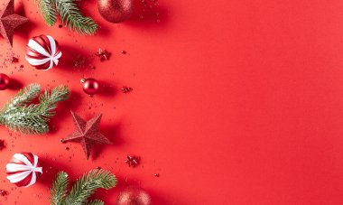 Noel konsepti. Kırmızı ladin dalları, çam kozalakları, kırmızı böğürtlenler, kırmızı zemin üzerinde yıldız ve çan olan Noel kırmızı toplarının en üst görüntüsü.