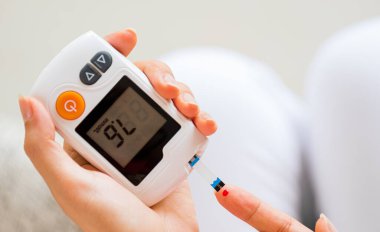 Dünya Diyabet Günü konsepti. Kan ile ellerinizi kapatın şeker testi için kan şekeri seviyesini Glikoz metreye göre kontrol edin.